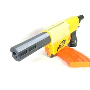 May include: A yellow and black Nerf toy gun with a gray barrel extension and an orange magazine. The gun has the word "NERF" printed on the side.