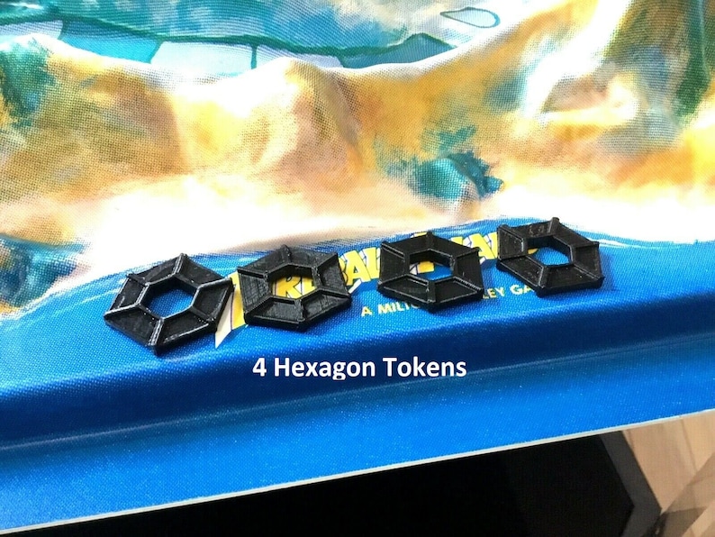 May include: Four black hexagon-shaped game tokens on a blue surface. The text "4 Hexagon Tokens" is printed below the tokens.