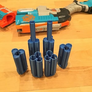 May include: Six blue plastic 3D printed Nerf dart clips. The clips are designed to hold multiple darts for easy reloading.