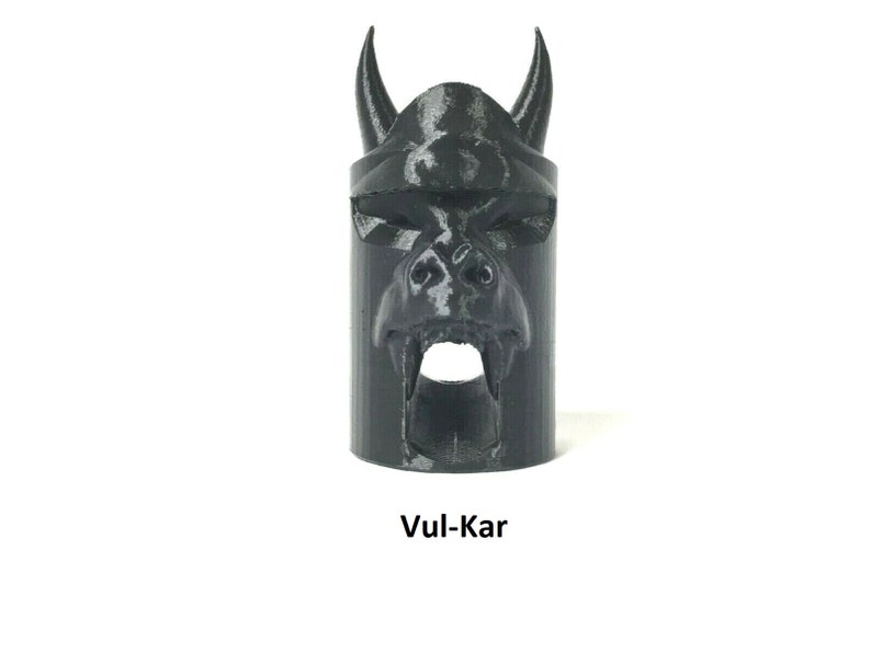 May include: Black plastic 3D printed object shaped like a demon's head with horns and fangs. The object has a hole in the mouth. The text "Vul-Kar" is printed below the object.