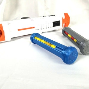 May include: Three blue, gray, and black plastic dart clips with a smiley face design. The clips are for a Nerf dart blaster.