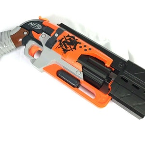 May include: Orange and black Nerf N-Strike Elite Disruptor toy gun with a brown grip and a black magazine. The gun has a zombie-themed design with a skull and crossbones logo.