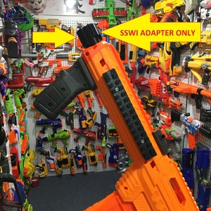 May include: Orange and black Nerf gun with a black grip and a black rail system. The gun is labeled "SSWI ADAPTER ONLY".