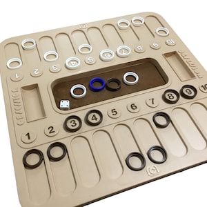 May include: A beige wooden game board with white and black rings, a blue ring, and a white die. The board has numbers 1 through 10 on it. The game is called "Qwixx".