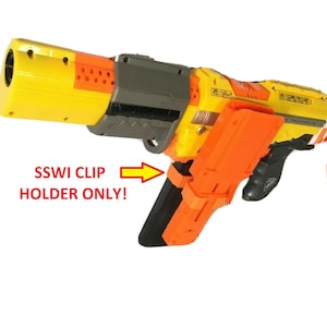May include: A yellow and orange toy gun with a black clip holder. The text "SSWI CLIP HOLDER ONLY!" is printed on the image.