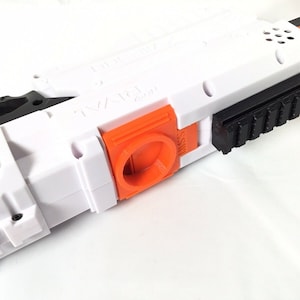 May include: A white and orange toy gun with a black rail on top. The gun has a textured grip and a trigger.