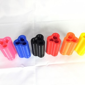 May include: Six 3D printed cylindrical organizers in different colors: pink, blue, black, red, orange, and yellow. Each organizer has three compartments.