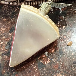 Peut inclure: Une d&eacute;coration de No&euml;l en forme de tarte en verre avec une cro&ucirc;te rouge et une garniture blanche. La d&eacute;coration a un cintre dor&eacute;.