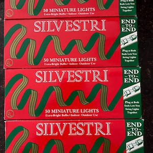 May include: Four red boxes of Silvestri 50 miniature lights. Each box has a green and gold ribbon design and the text "50 Miniature Lights Extra-Bright Bulbs Indoor/Outdoor Use". The boxes also say "End to End" and "Plug at Both Ends Lets You String Lights Together".