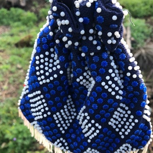 May include: A blue and white beaded drawstring bag with a fringe trim. The bag is decorated with a geometric pattern of white and blue beads.