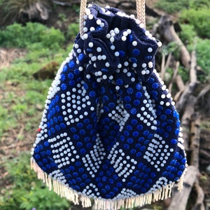 May include: A blue and white beaded drawstring bag with a fringe trim. The bag is made of small, round beads and has a geometric pattern.