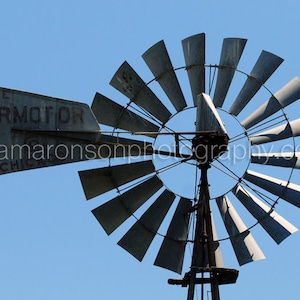 May include: A vintage metal windmill with a sign that reads "The Aermotor Chicago". The windmill has a large, circular fan with many blades.