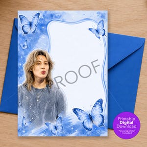 May include: A rectangular stationery sheet featuring a portrait of a person with shoulder-length blonde hair, wearing a grey shirt and a cross necklace. The design includes blue watercolor butterflies, sparkles, and the word PROOF in grey text.