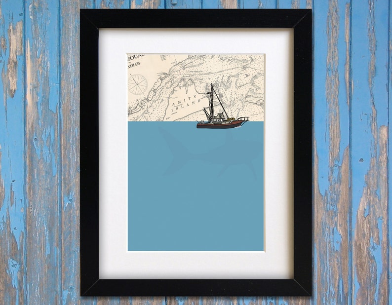 May include: Framed art print featuring a nautical map with a boat illustration. The map shows the area around Amity Island, with a blue ocean below. The print is in a black frame.