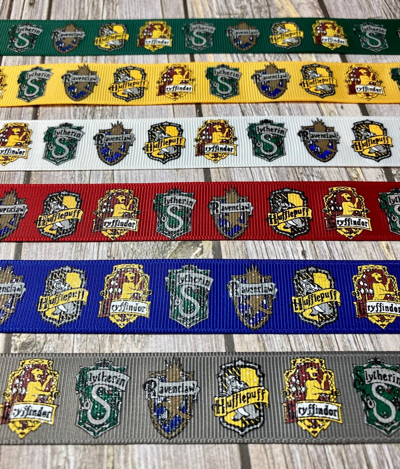 Op de afbeelding: Lint met verschillende huisschilden uit een fantasieserie. De linten zijn groen, geel, wit, rood, blauw en grijs. Elk lint toont de schilden van Zwadderich, Ravenklauw, Huffelpuf en Griffoendor.