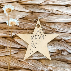 May include: A gold star-shaped tag with the word "NOVA" engraved on it. The tag is decorated with small stars and dots.
