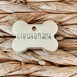 May include: A gold bone-shaped dog tag with the word "Lieutenant" engraved on it.