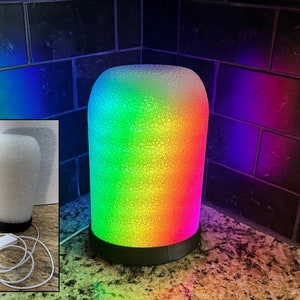 May include: A white and rainbow colored lamp with a textured surface. The lamp is plugged in and has a remote control.