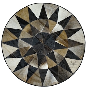 May include: A round, black and brown cowhide rug with a starburst pattern. The rug is made of different pieces of leather sewn together. The rug has a black border.