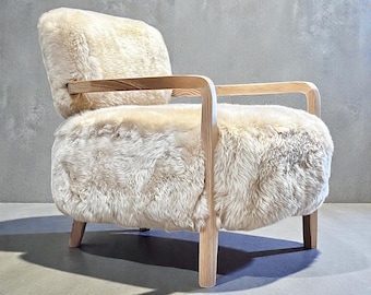 May include: A cream-colored armchair with a sheepskin seat and backrest. The chair has a light wood frame and armrests. The legs are also made of light wood. The chair is designed for comfort and style.