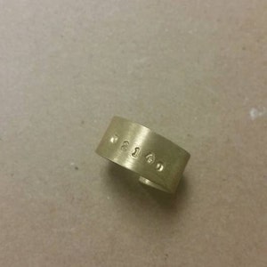 May include: A gold-coloured metal ring with the numbers "0215" engraved on it.