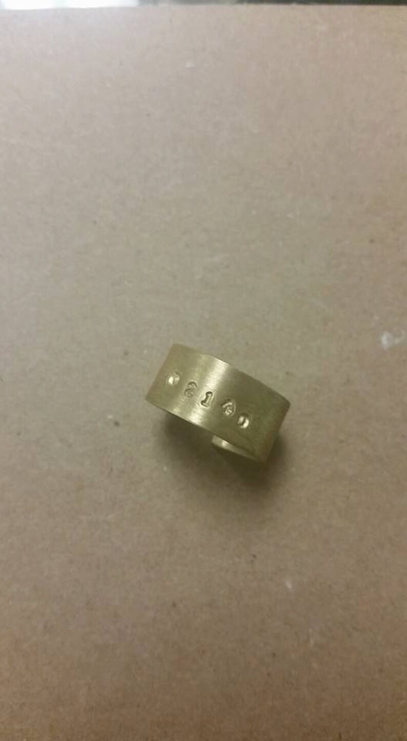 Puede incluir: Un anillo de metal de color dorado con los n&uacute;meros "0215" grabados.