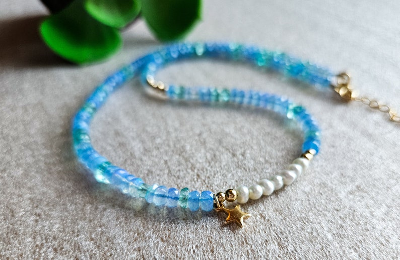 Peut inclure: Un collier d&eacute;licat en pierres pr&eacute;cieuses bleues et vertes avec une seule perle et un pendentif &eacute;toile en or.