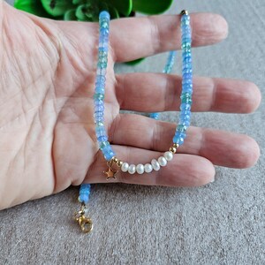 Peut inclure: Un collier d&eacute;licat en pierres bleues et blanches avec un pendentif &eacute;toile en or et des accents de perles.