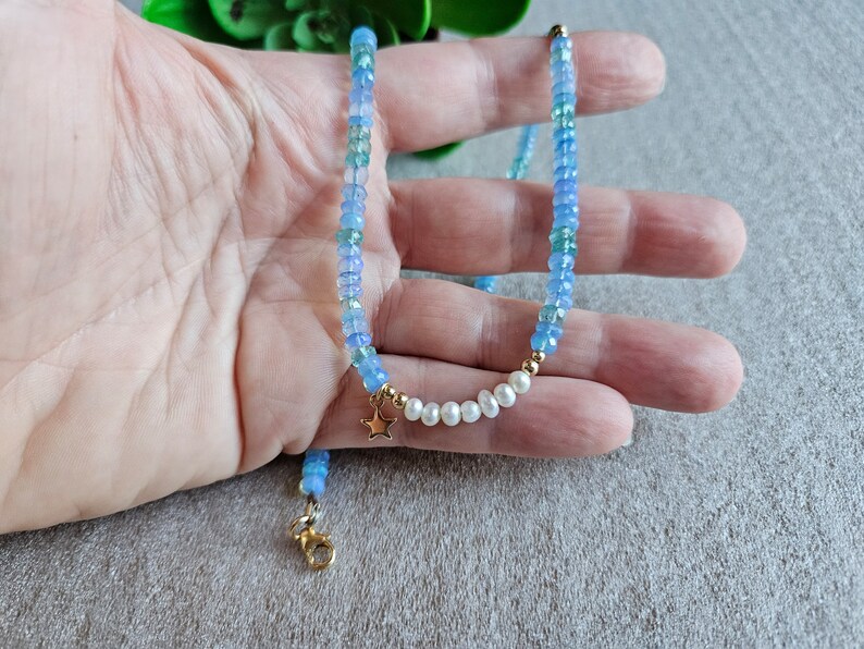 Peut inclure: Un collier d&eacute;licat en pierres bleues et blanches avec un pendentif &eacute;toile en or et des accents de perles.