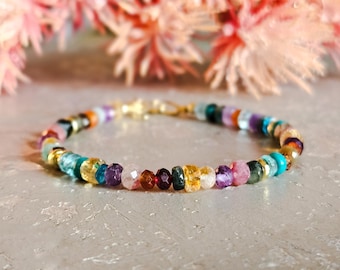 Peut inclure: Un bracelet de perles multicolores avec un fermoir doré. Le bracelet présente une variété de pierres précieuses dans les tons de bleu, vert, jaune, violet, rose et marron. Le bracelet mesure environ 18 cm de long.