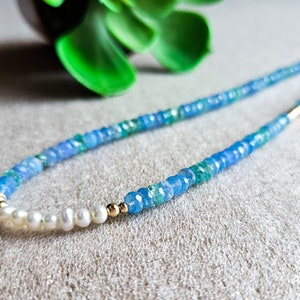 Peut inclure: Un collier de pierres pr&eacute;cieuses bleues et vertes avec un pendentif &eacute;toile en or et des accents de perles blanches.