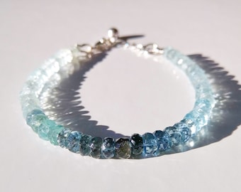 Peut inclure: Un bracelet délicat composé de perles d'aigue-marine graduées, allant d'un bleu foncé à un bleu clair, avec un fermoir argenté.