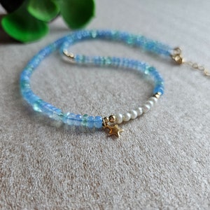 Peut inclure: Un collier d&eacute;licat en perles bleues et blanches avec un pendentif &eacute;toile en or. Le collier est compos&eacute; de petites perles rondes et pr&eacute;sente un design simple et &eacute;l&eacute;gant.