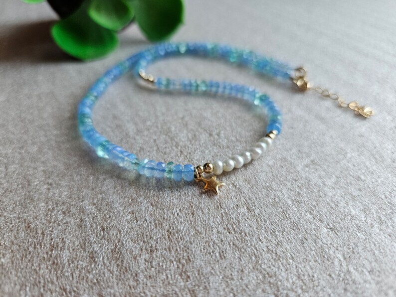 Peut inclure: Un collier d&eacute;licat en perles bleues et blanches avec un pendentif &eacute;toile en or. Le collier est compos&eacute; de petites perles rondes et pr&eacute;sente un design simple et &eacute;l&eacute;gant.