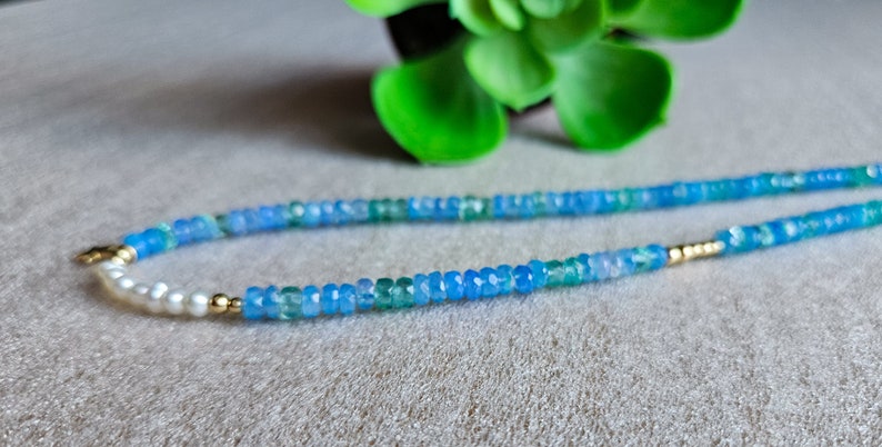 Peut inclure: Un collier d&eacute;licat compos&eacute; de perles de pierres pr&eacute;cieuses bleues et vertes, entrecoup&eacute;es de perles blanches et d'accents dor&eacute;s.