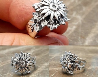 May include: A silver ring featuring a detailed sunflower design with a small clear stone in the center.