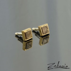 May include: A pair of gold cufflinks with square-shaped brown stone insets.