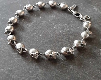 May include: A silver bracelet with a chain made of skull-shaped beads.