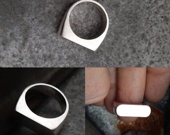 May include: A silver ring with a flat, rectangular top. The ring is shown from the side and the top.