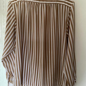 May include: A long-sleeved brown and white striped blouse with a button-up front.
