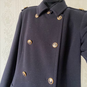 May include: A navy blue double-breasted peacoat with gold buttons. The buttons have a decorative design.