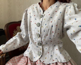May include: A white linen jacket with a floral print and silver buttons. The jacket has a V-neck and long sleeves.