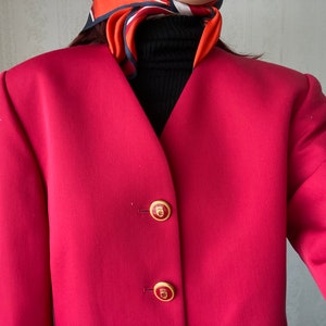 May include: A red blazer with gold buttons. The buttons have a crest design.