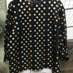 May include: A black sheer blouse with a polka dot pattern. The dots are silver, gold, and copper.