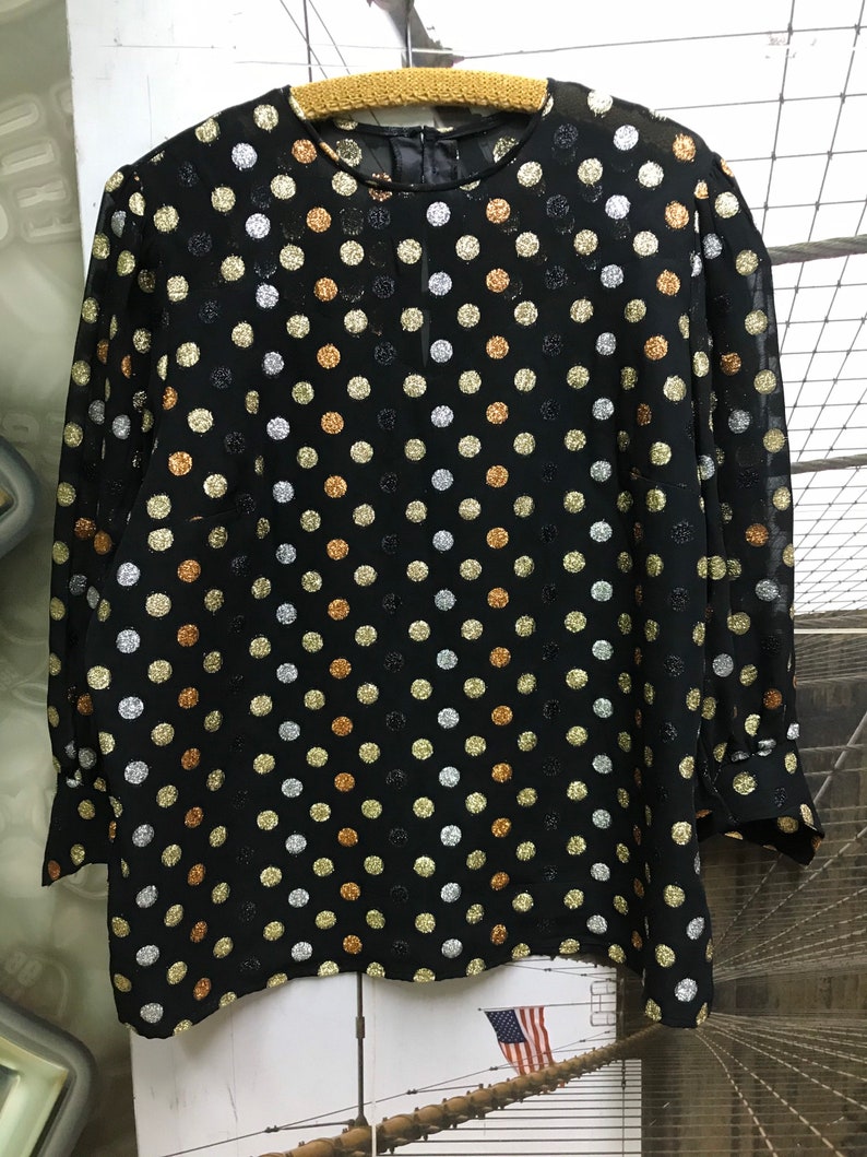 May include: A black sheer blouse with a polka dot pattern. The dots are silver, gold, and copper.