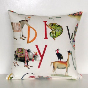 May include: Square white decorative pillow with colorful illustrations of animals and the letters D, I, Y, and W. The animals include a donkey, a chameleon, a yak, a vulture, and a llama. The letters are in orange and red.