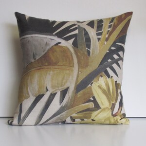 Peut inclure: Un coussin décoratif avec un motif de feuilles tropicales dans des tons de brun, jaune et gris. Le coussin est fait d'un tissu doux et texturé.
