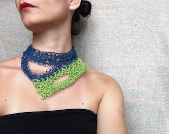 Può includere: Una donna indossa una collana a strati realizzata con filato di cotone lavorato a uncinetto blu e verde. La collana è un pezzo di grande impatto e aggiunge un tocco di colore all'outfit.