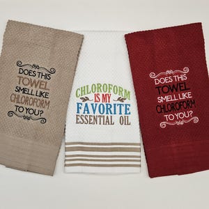 May include: Three embroidered towels in tan, white, and burgundy. The tan and burgundy towels have the text "DOES THIS TOWEL SMELL LIKE CHLOROFORM TO YOU?". The white towel says "CHLOROFORM IS MY FAVORITE ESSENTIAL OIL".