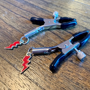 May include: Two silver clamps with black rubber tips and red lightning bolt charms attached.